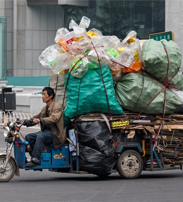 A man is seen on a freight bike loaded with recyclable materials. 