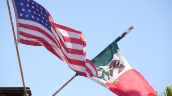 Mexican tricolor and American flag waving on wind.